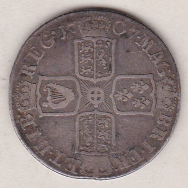 1707 E silver shilling coin featuring the draped bust of Queen Anne on the Obverse. The crowned cruciform shield on the Reverse.