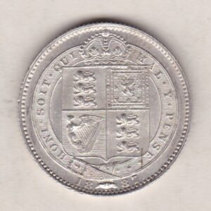 1887 Silver Shilling coin featuring Queen Victoria on the Obverse. The Reverse features the crowned Royal shield within Garter, with divided date below.