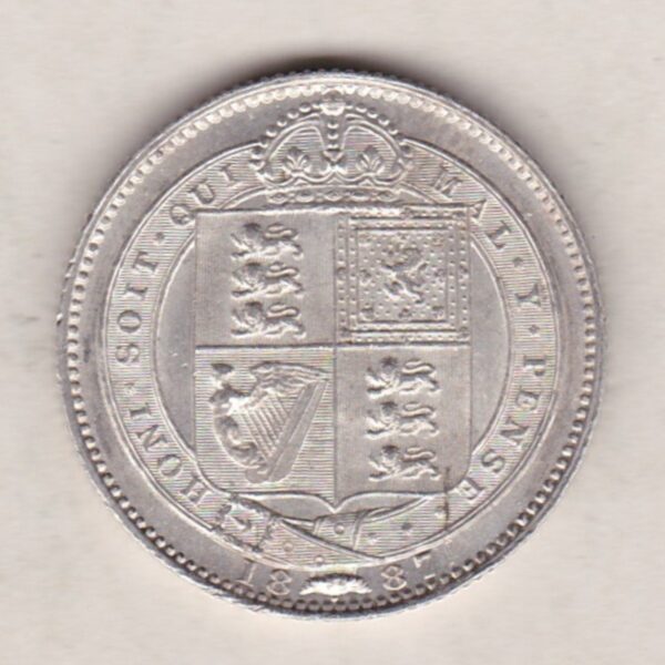 1887 Silver Shilling coin featuring Queen Victoria on the Obverse. The Reverse features the crowned Royal shield within Garter, with divided date below.