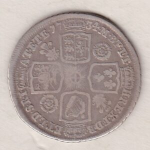 1734 silver shilling coin featuring a laureate and draped bust of George II. The crowned cruciform shields with central Garter star on the Reverse.