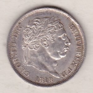 1818 silver shilling coin featuring King George III on the Obverse. The Reverse features an ornate crowned Royal shield overlaid with another shield.