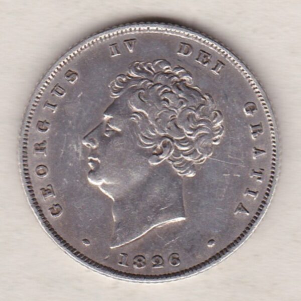 1826 silver shilling coin featuring King George IV on the Obverse. The Reverse has a crowned lion, legend around, national flower emblems below.