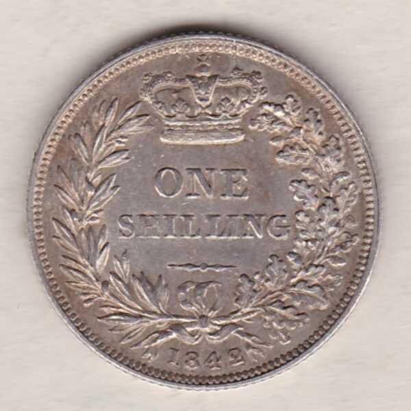 1842 silver shilling coin featuring Queen Victoria young head on the Obverse. The Reverse has a crown, laurel and oak leaves within an open wreath.