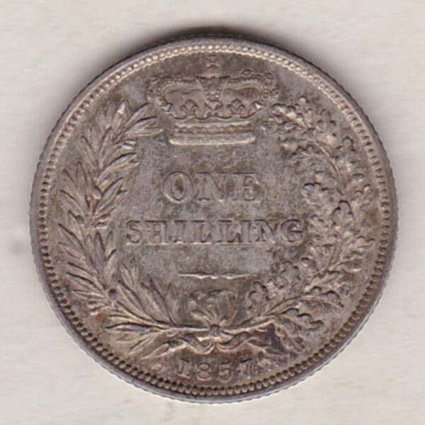 1857 silver shilling coin featuring Queen Victoria young head on the Obverse. The Reverse has a crown, laurel and oak leaves within an open wreath.