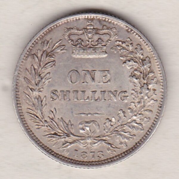 1873 silver shilling coin featuring Queen Victoria young head on the Obverse. The Reverse has a crown, laurel and oak leaves within an open wreath.