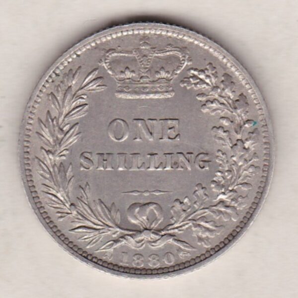 1880 silver shilling coin featuring Queen Victoria young head on the Obverse. The Reverse has a crown, laurel and oak leaves within an open wreath.