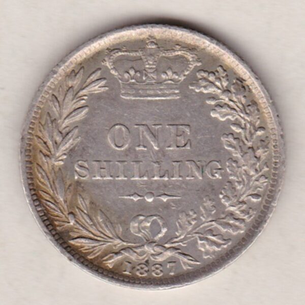 1887 silver shilling coin featuring Queen Victoria young head on the Obverse. The Reverse has a crown, laurel and oak leaves within an open wreath.