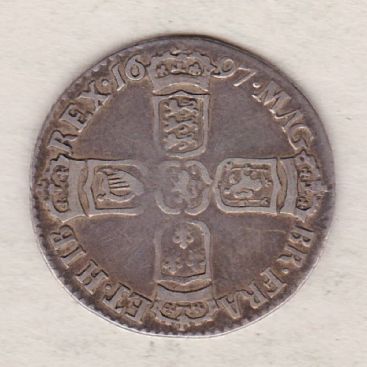 1697 silver sixpence coin featuring King William III on the obverse. The Reverse is completed with crowned cruciform shields around central lion.