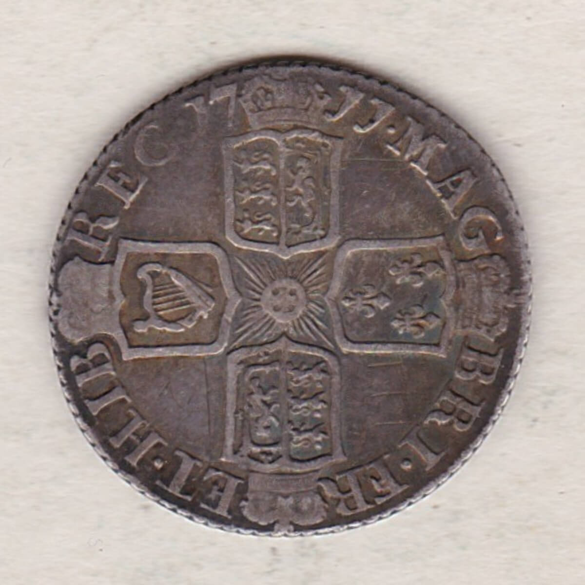 1711 silver sixpence coin featuring Queen Anne on the obverse. The Reverse is completed with crowned cruciform shields around central Garter star.