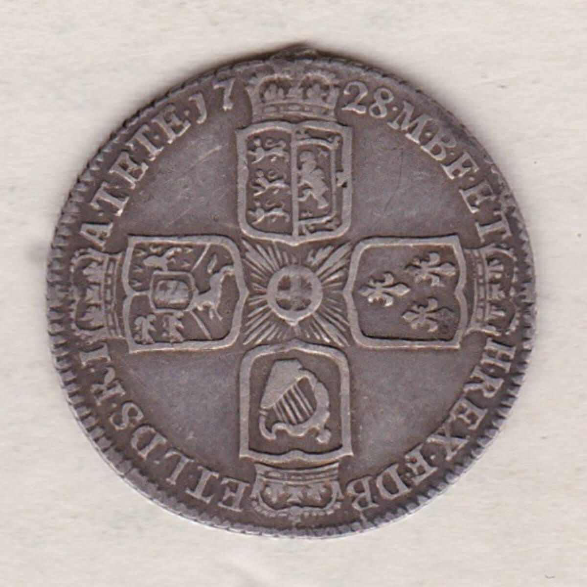 1728 silver sixpence coin featuring a laureate bust of George II. There are four crowned shields arranged in a cross on the Reverse.