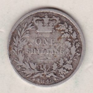 1846 silver shilling coin featuring Queen Victoria young head on the Obverse. The Reverse has a crown, laurel and oak leaves within an open wreath.