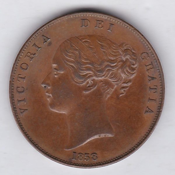 1858 copper penny coin featuring the young head portrait of Queen Victoria on the Obverse. The coin depicts Britannia seated to the right on the Reverse.