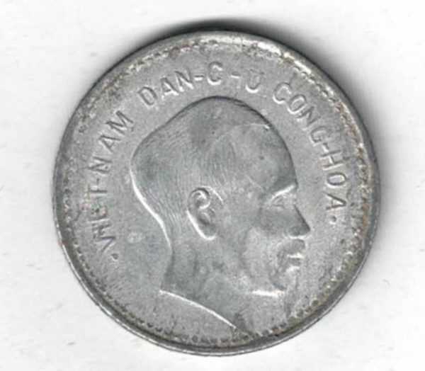 1946 Vietnam Aluminium One Dong Coin. The obverse features the bust of Ho Chi Min. The reverse features a wheat branch with denomination.