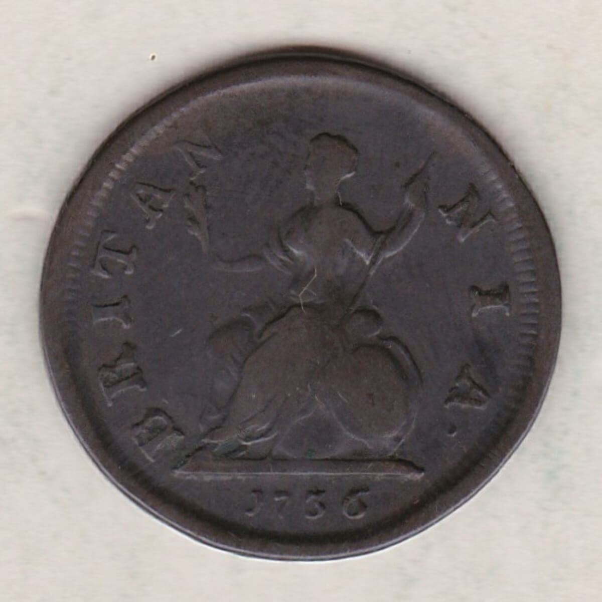 1736 copper farthing coin featuring the portrait of King George II on the Obverse. Britannia seated facing left on the Reverse.