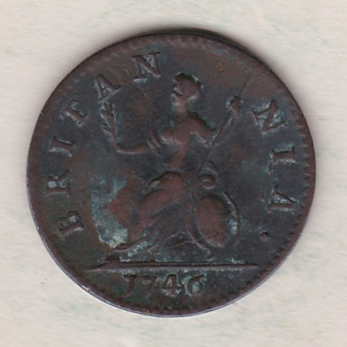 1746 copper farthing coin featuring the portrait of King George II on the Obverse. Britannia seated facing left on the Reverse.