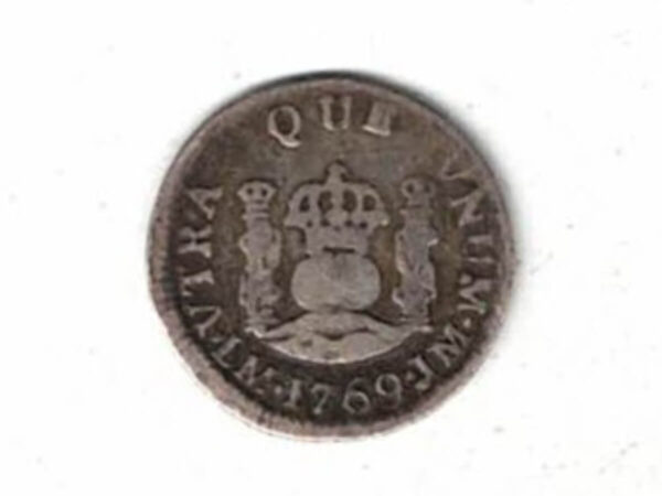 1769 M Mexico Silver Half Real Coin. The obverse features a crowned shield flanked by stars. The reverse features pillars with with banner and date below. 