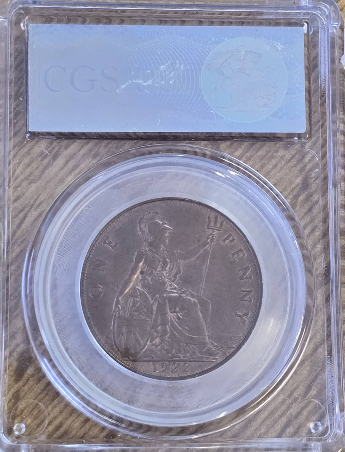 1922 Bronze Penny coin. The obverse features the portrait of King George V. The coin depicts Britannia seated to the right on the Reverse.