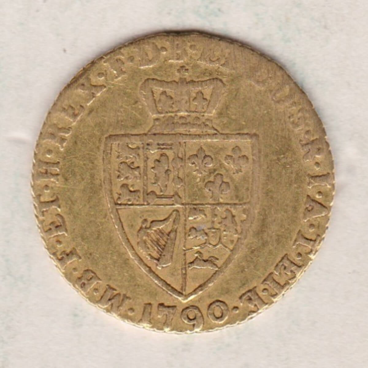 1790 Gold Half Guinea Coin featuring the laureate head portrait of King George III on the obverse. The reverse features the crowned quartered shield.