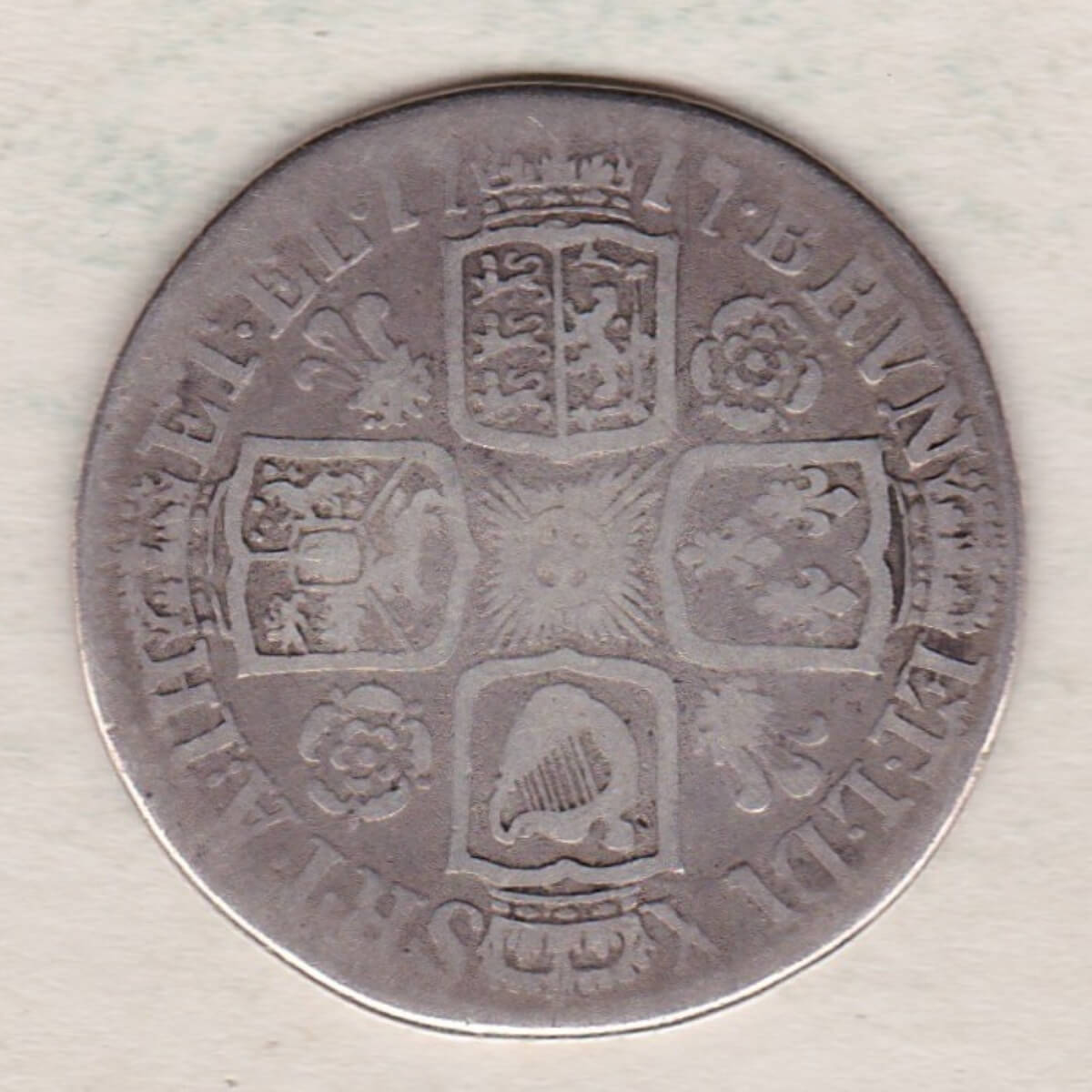 1717 silver shilling coin featuring a laureate and draped bust of George I. The crowned cruciform shields with central Garter star on the Reverse.