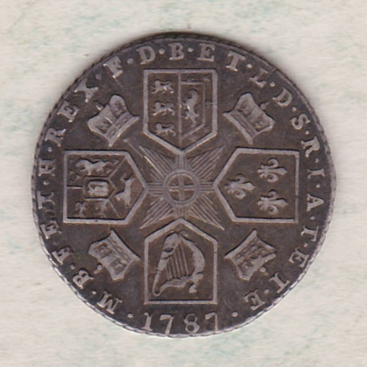 1787 silver sixpence coin featuring a laureate bust of George III. This coin is the variety with a semee of hearts in Hanoverian arms on the Reverse.