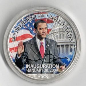 Boxed 2009 Silver USA One Ounce Eagle Colourised Barack Obama Coin. An eagle is on the reverse. The coin contains one ounce of 999 fine silver.